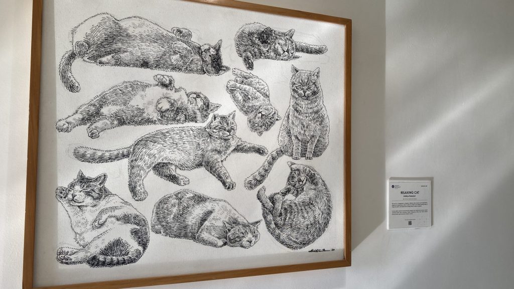 客房走廊上的貓咪素描畫作，旁邊附有作品介紹牌