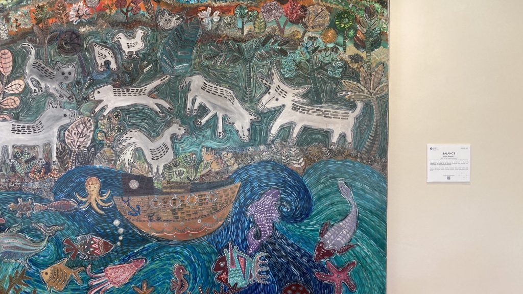 客房走廊上色彩豐富的動物與海洋主題畫作，旁邊附有作品介紹牌